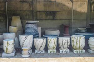 Storefront displaying a variety of ceramic pots and planters against a rustic brick wall. Ideal for home decor and gardening enthusiasts photo