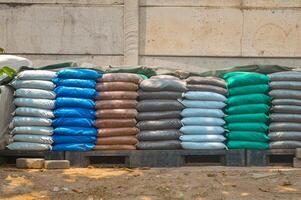Stacked colorful fertilizer bags on a pallet, showcasing various types for agricultural use. Essential supplies for farming and gardening photo