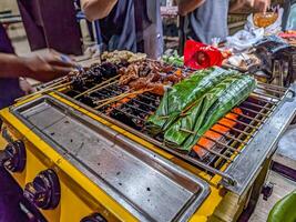 Traditional Indonesian angkringan street food stall with assorted grilled skewers, vibrant night market scene. Perfect for capturing the essence of local cuisine and culture photo