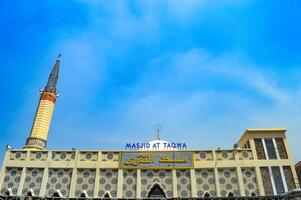 A beautiful mosque with yellow and white minarets under a bright blue sky, showcasing intricate Islamic architecture. translation on mosque The name of masjid at taqwa photo