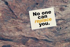 A piece of wood with a note on it that says no one can replace you photo