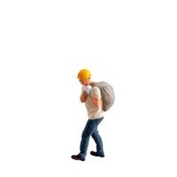 Miniature construction worker carrying a heavy sack on his back isolate on white background with clipping path photo