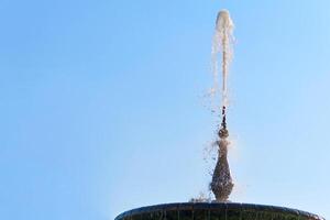 Fountain with shining clear liquid on a sky with clouds background photo