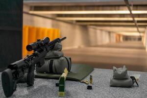 Precision sniper rifle on shooting range mat with ammunition. photo