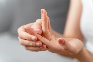 Closeup young woman sitting on sofa holds her wrist. hand injury, feeling pain. Health care. photo
