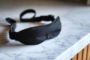 Black sleep mask on a marble countertop in a modern setting. photo