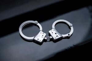 Close-up of metal handcuffs on a dark, reflective surface. photo