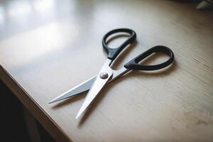 A pair of open scissors on a wooden desk, ready for use. photo