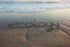The word 'ecology' spelled with twigs on a sandy beach near the ocean. photo