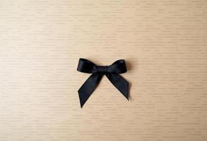 Elegant black ribbon bow placed on a light wooden background. photo
