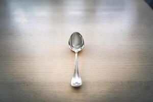 Elegant silver spoon on a light wooden surface. photo