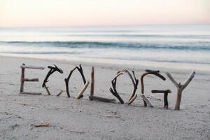 Ecology spelled with driftwood on a serene beach at sunrise. photo