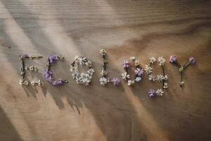 The word 'Ecology' spelled with small flowers on a wooden background. photo