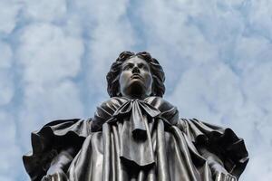 Low-angle shot of a historical statue against a cloudy sky. photo