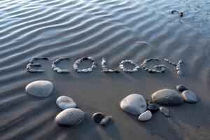 Eco-friendly message spelled with stones on a ripple-marked sandy beach. photo