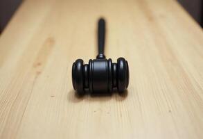 A black gavel on a wooden surface, symbolizing justice and authority. photo