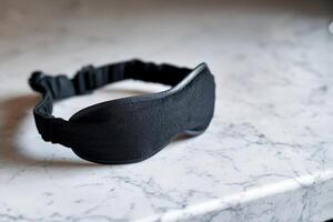Black sleep mask on a marble surface. photo