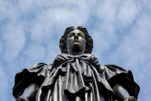 Low-angle view of a statue of a woman against a partly cloudy sky. photo