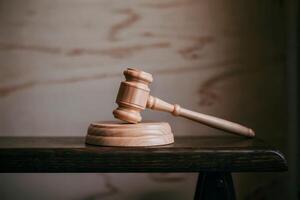 Wooden gavel and sound block on a dark wooden table in a dimly lit room. photo