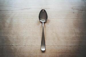 Single silver spoon placed neatly on a wooden table. photo