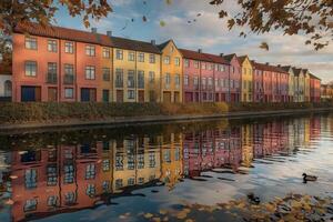 Colorful buildings alongside a reflective canal with autumn leaves. photo