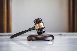A wooden gavel and sound block on a marble surface in a courtroom. photo