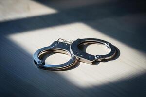 Close-up of metal handcuffs on a wooden surface under natural light. photo