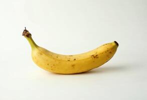 Ripe yellow banana with brown spots on a plain white background. photo