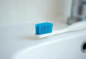 Close-up of a blue toothbrush on a white sink in a bathroom. photo