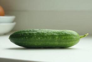 Fresh green cucumber on a white kitchen countertop. photo
