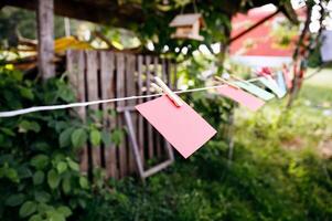 Clothespins, colorful paper cards, hanging on string, outdoor garden background, summer day, rustic scene, communication and decor concept photo