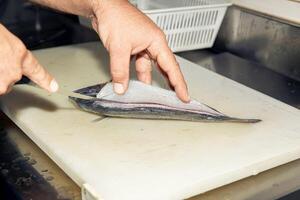 Preparing fresh fish fillet, hands using knife, kitchen cutting board, close-up of seafood, culinary concept photo
