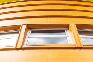 Curved modern wooden facade with geometric design and rectangular windows, contemporary architecture concept photo