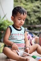 Cute Indian boy holding Indian National Flag in his hangs at home balcony. Bright portrait of happy child sitting on the table with national flag photo