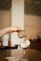 Affogato coffee, hot espresso pouring over ice cream in glass on table. photo