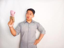Young Asian man smiling happy while holding wallet and showing paper money from his wallet photo