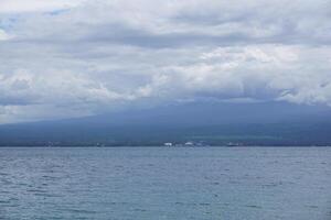 A boat is sailing in the ocean with a mountain in the background photo