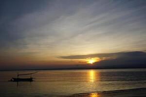 A boat is sitting on the beach at sunset photo