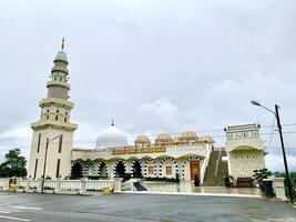 The mosque is white with a large minaret on top. photo