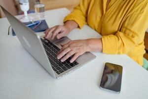 Overview of hands of young businesswoman or student typing on laptop keyboard by desk while working over presentation photo