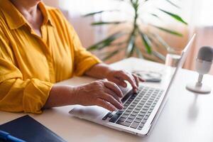 Overview of hands of young businesswoman or student typing on laptop keyboard by desk while working over presentation photo