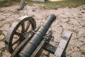 Cannon on a carriage located on a white stone pedestal near the arsenal building in Mirow Castle. Sites of Poland. Architecture of World Tourism. photo