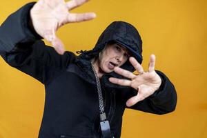 funny portrait of middle aged woman dressed as angry rapper in black tracksuit gesturing posing on colorful background photo