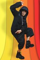 beautiful middle aged woman in black sweatshirt posing like a rapper in aggressive attitude on colorful background photo