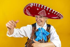 portrait of a happy middle-aged woman smiling in front of a yellow background having fun dancing dressed as a Mexican mariachi with sombrero photo