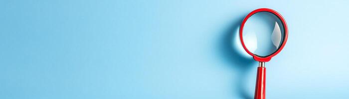 Close-up of a red magnifying glass on a light blue background. The image represents exploration, search, and discovery with simplicity and clarity. photo