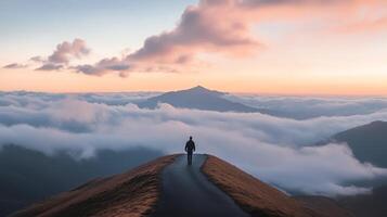 A lone person walking on a mountain path surrounded by clouds during a stunning sunset, capturing a moment of solitude and natural beauty. photo