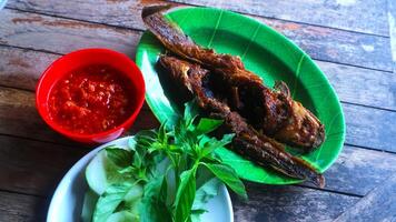 A plate of fish and vegetables on a wooden table photo