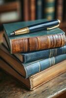 A pen is sitting on top of a stack of books. The books are of different sizes and colors, and the pen is black and gold. Concept of organization and order photo