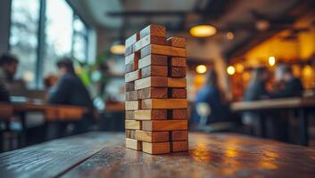 A stack of wooden blocks on a table in a restaurant. The blocks are arranged in a pyramid shape, and the scene is set in a busy restaurant with people sitting at tables and chairs photo